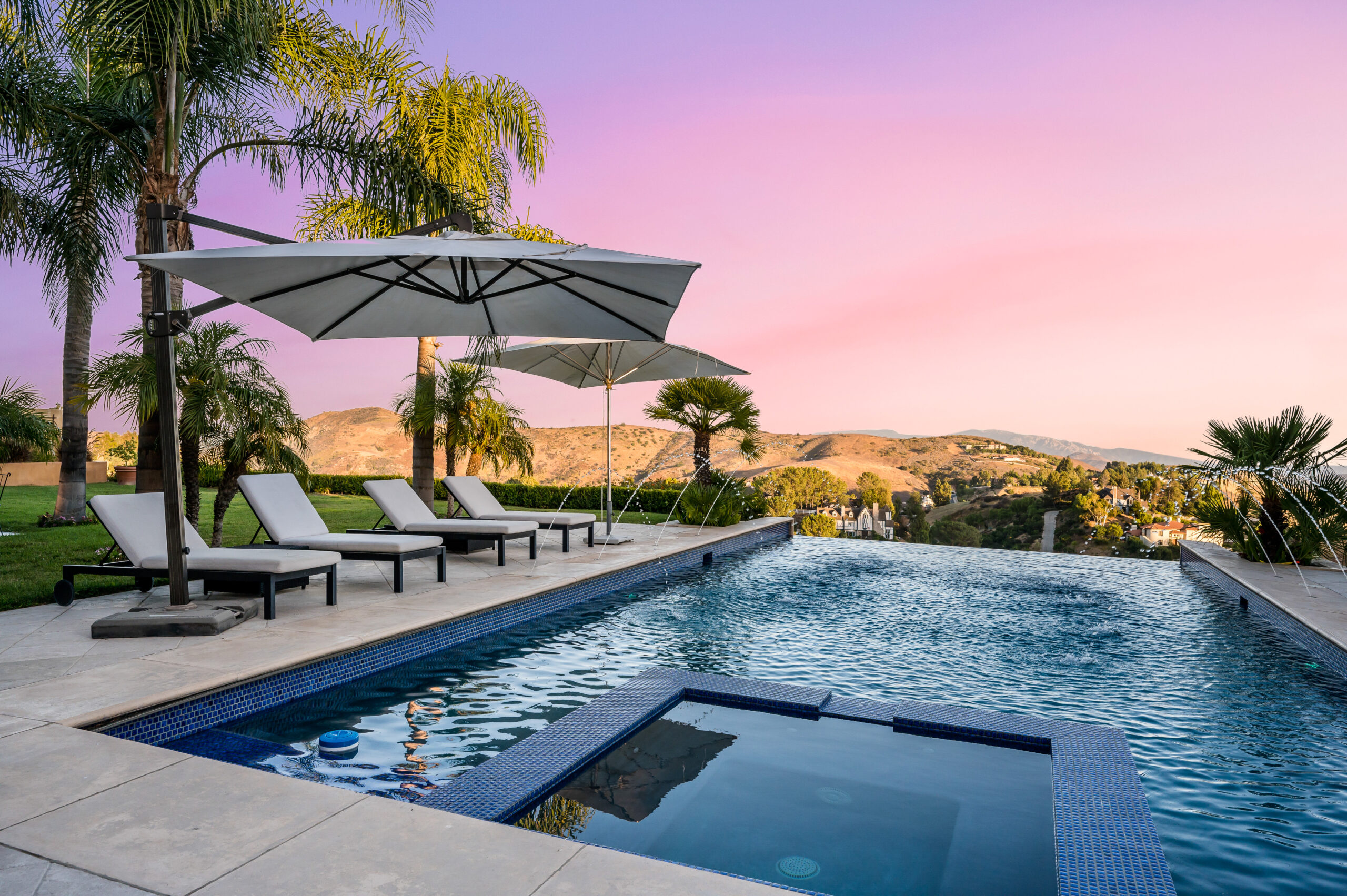 Sunset view of a serene pool with loungers and umbrellas