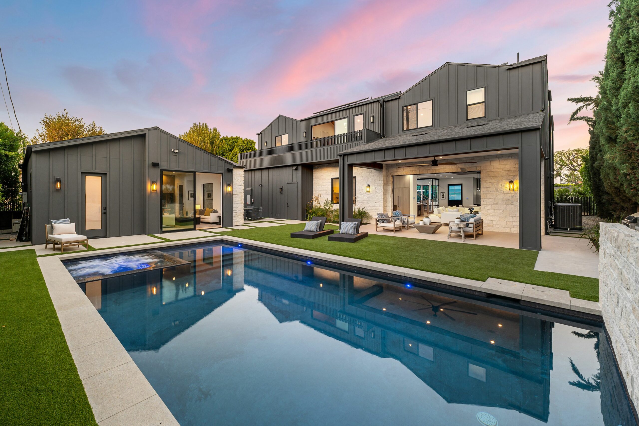 Modern luxury home with sleek design, pool, and spacious outdoor seating area at sunset.
