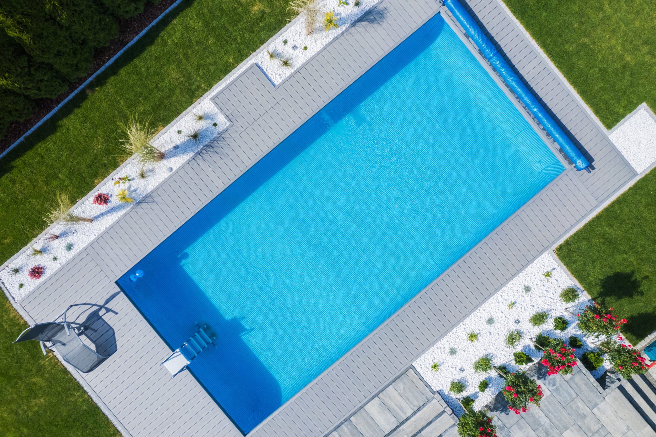 Perfectly Maintained Outdoor Swimming Pool Surrounded by Green Lawn and Landscaped Flower Beds. Residential House Backyard Garden Design. Recreational and Resting Area. Aerial View.