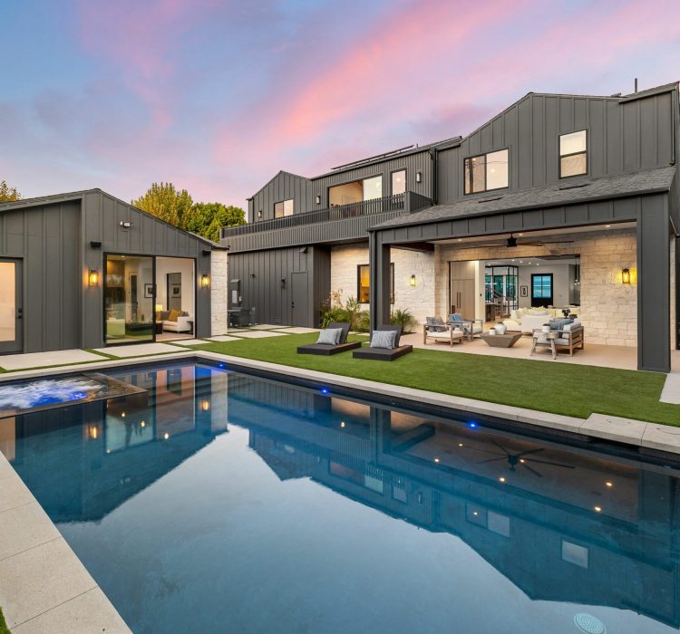 Modern luxury home with sleek design, pool, and spacious outdoor seating area at sunset.