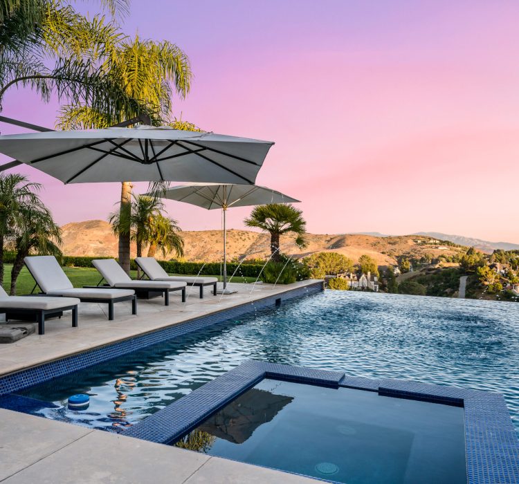 Sunset view of a serene pool with loungers and umbrellas